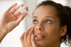 Woman putting eye drops in her eye