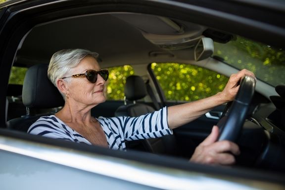 Older woman driving a silver car
